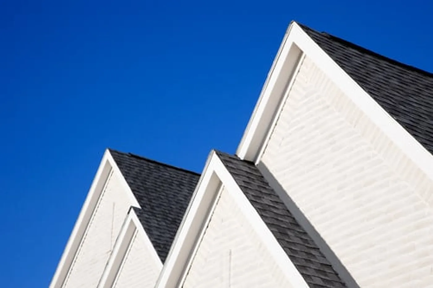 White gabled rooflines against a clear blue sky on a Long Island home