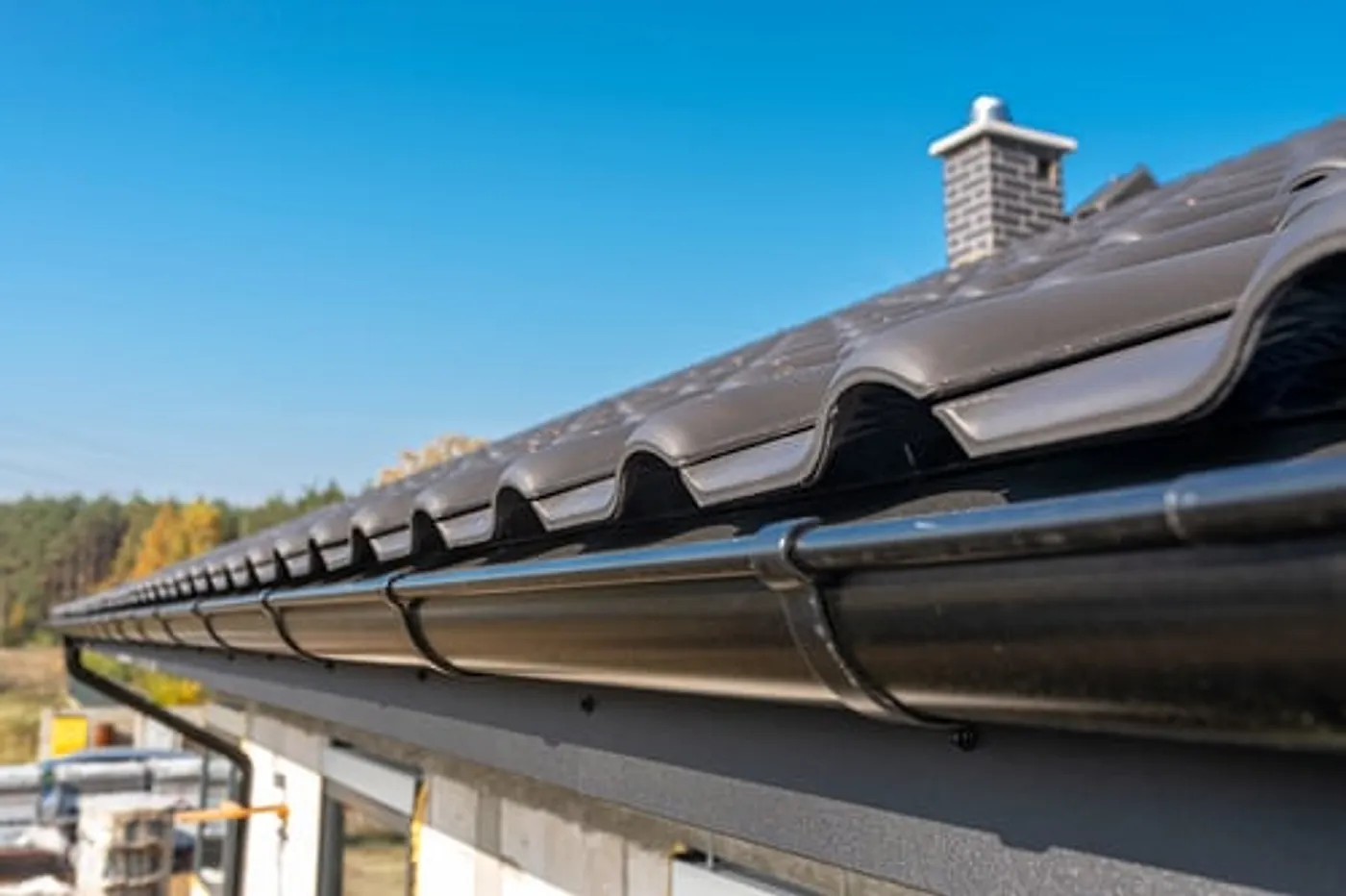 Roofline, chimney and gutter detail on a home under a clear sky