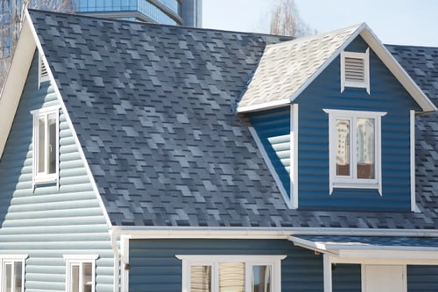 Blue and white Long Island home with a shingle roof and clean seamless gutter line