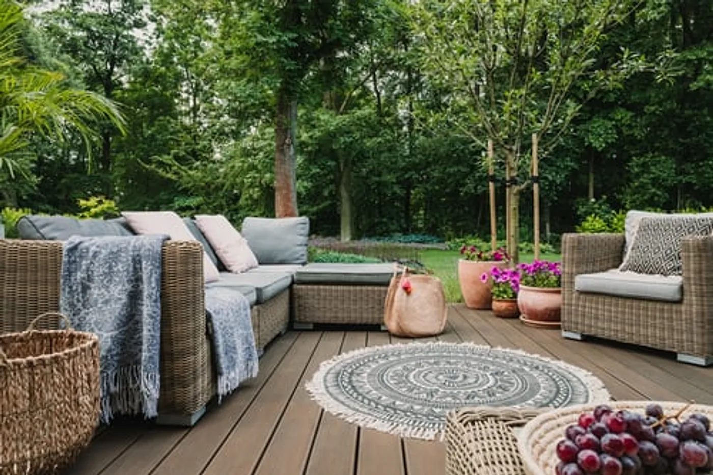 Finished backyard deck with outdoor lounge furniture surrounded by mature trees