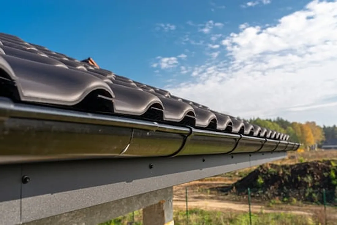 Clean seamless gutter run installed along a roof edge against a bright sky